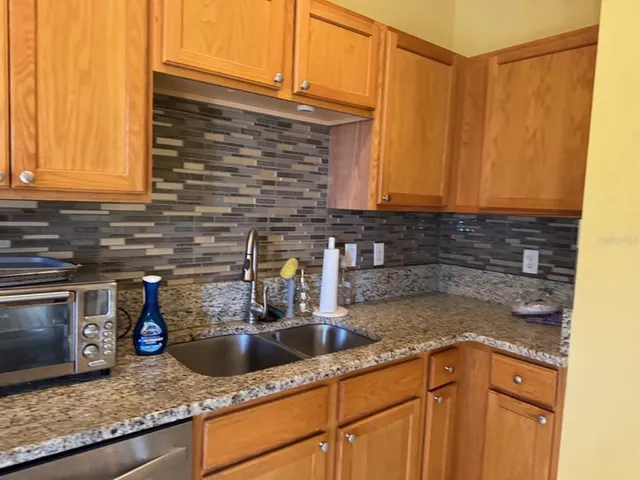 a kitchen with granite countertop a sink a stove and cabinets