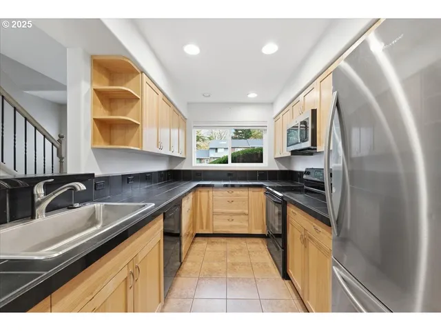 a view of a kitchen with stainless steel appliances granite countertop a sink and a refrigerator