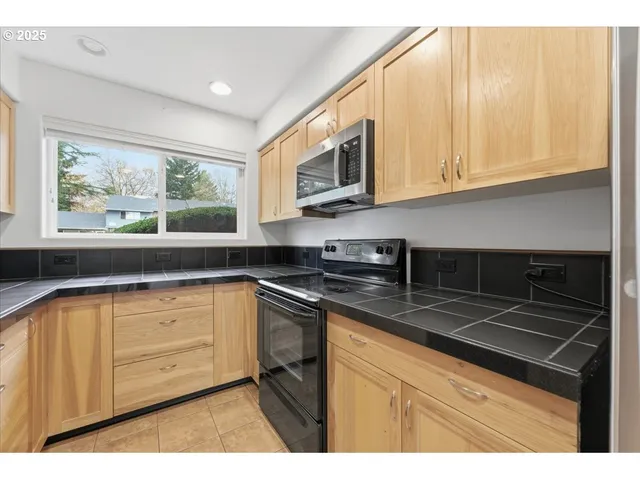 a kitchen with stainless steel appliances granite countertop a sink a stove and cabinets