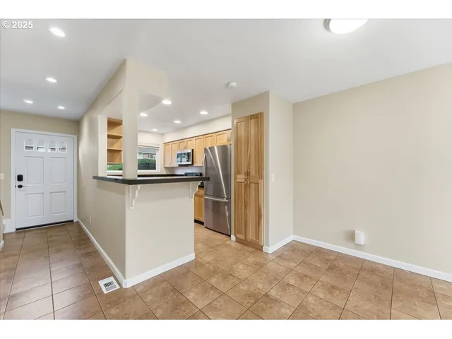a kitchen with stainless steel appliances kitchen island granite countertop a refrigerator a sink and a stove