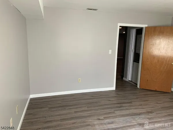a view of an empty room with wooden floor and closet