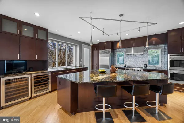 a kitchen with stainless steel appliances granite countertop a stove top oven a sink a dining table and chairs with wooden floor