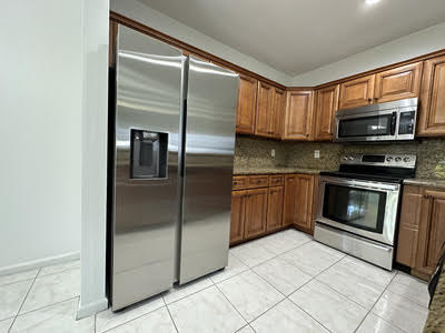 140 Baldwin Boulevard Greenacres, FL 33463 - Photo 2 of 12 a kitchen with stainless steel appliances granite countertop a refrigerator a stove a sink and a microwave