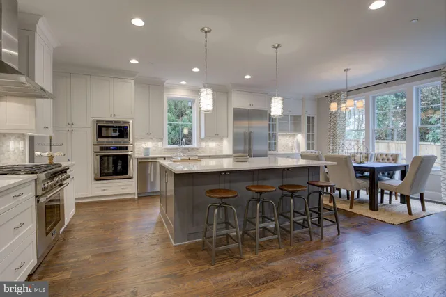 a kitchen with stainless steel appliances granite countertop a stove top oven a sink dishwasher a dining table and chairs with wooden floor