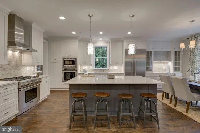 a kitchen with stainless steel appliances granite countertop a stove a sink a kitchen island with chairs and wooden floor
