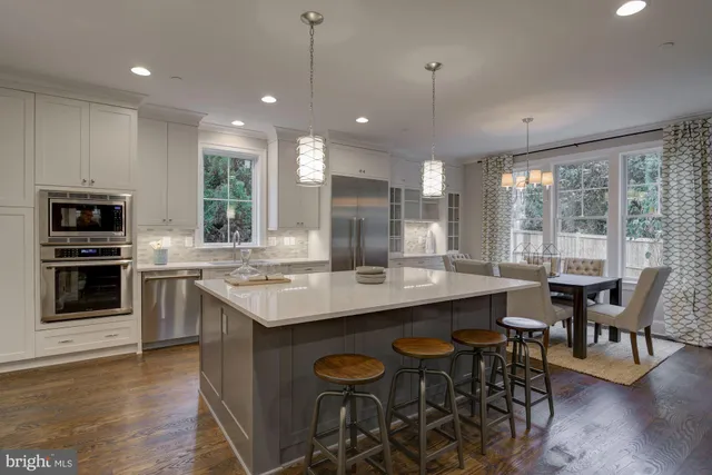 a kitchen with stainless steel appliances granite countertop a stove a refrigerator a kitchen island a dining table and chairs