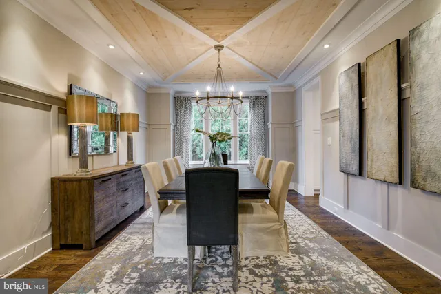 a dining room with wooden floor a chandelier a wooden table and chairs