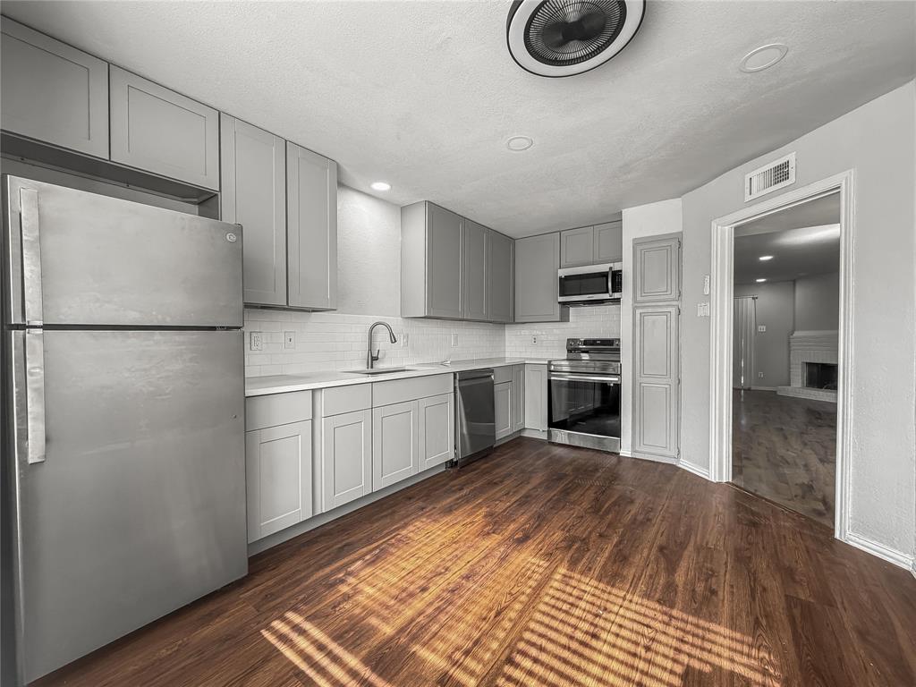 5840 Spring Valley Road, Unit 1104 Dallas, TX 75254 - Photo 11 of 16 Kitchen featuring stainless steel appliances, light gray cabinetry, white subway tile backsplash, and wood-finish flooring