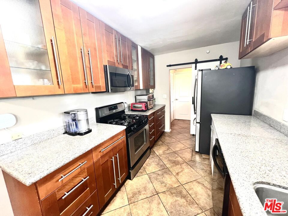 4340 Sepulveda Boulevard Sherman Oaks, CA 91403 - Photo 22 of 30 a kitchen with stainless steel appliances granite countertop a sink stove and refrigerator