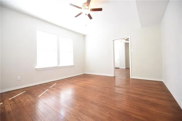 a view of an empty room with wooden floor and a window