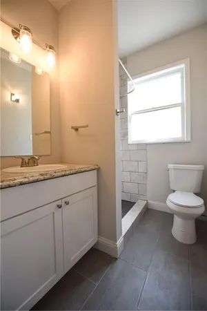 a bathroom with a granite countertop toilet a sink and a mirror