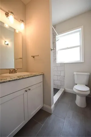 a bathroom with a granite countertop toilet a sink and a mirror