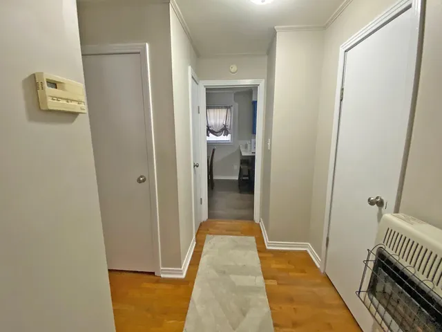 a view of a hallway with wooden floor and a bathroom