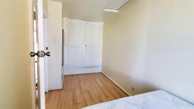 a view of a hallway with wooden floor and closet area