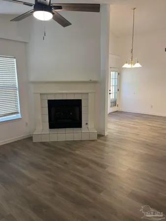 a view of an empty room with wooden floor fireplace and a window