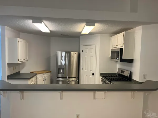 a kitchen with stainless steel appliances granite countertop a sink and a stove top oven with wooden floor