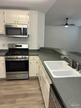 a kitchen with stainless steel appliances a stove microwave and sink