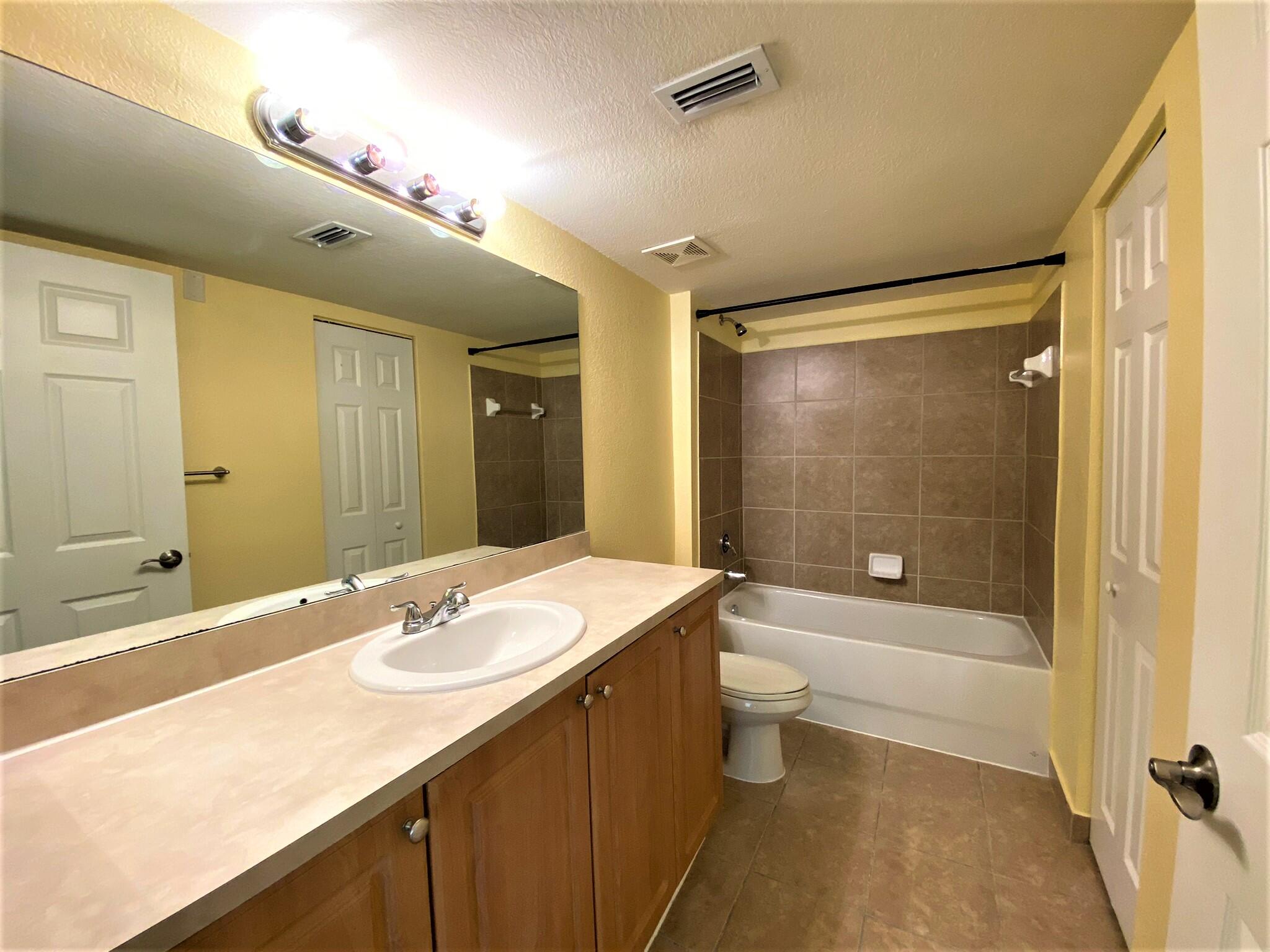 6768 Heritage Grande, Unit 106 Boynton Beach, FL 33437 - Photo 17 of 56 a bathroom with a granite countertop sink toilet and shower