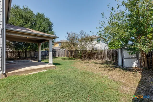 a view of a backyard with table and chairs and a large tree