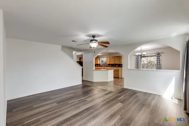 a view of a kitchen and an empty room with wooden floor