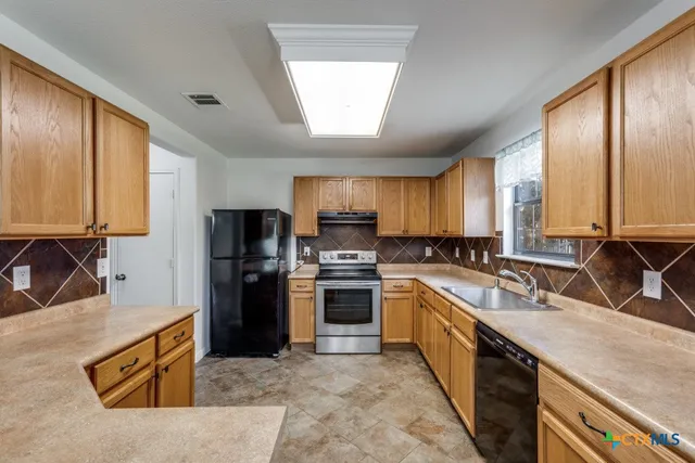 a large kitchen with stainless steel appliances granite countertop a sink stove and refrigerator