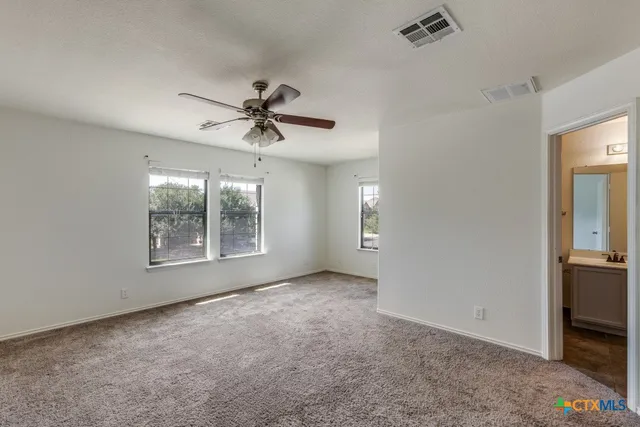 en empty room with windows and ceiling fan