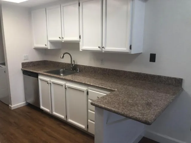 a kitchen with granite countertop a sink white cabinets and a granite counter tops