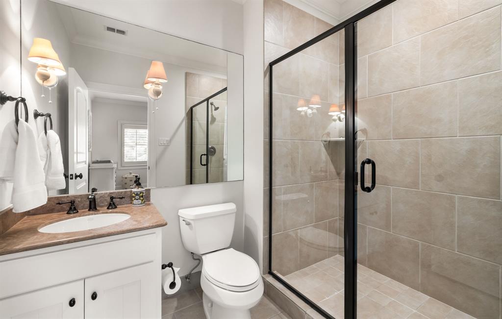 4715 Purdue Avenue Dallas, TX 75209 - Photo 21 of 30 a bathroom with a toilet a sink a mirror a shower and vanity