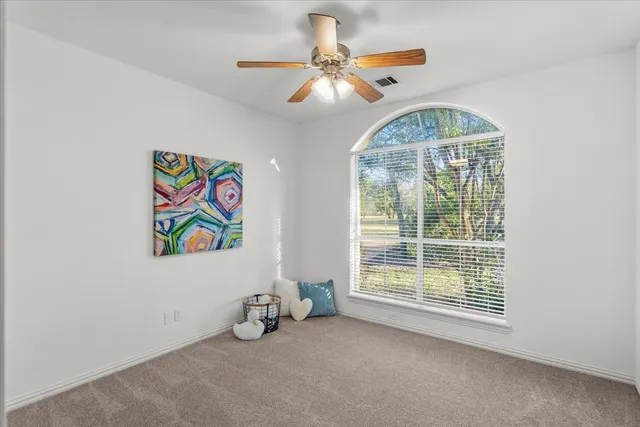 an empty room with windows and fan