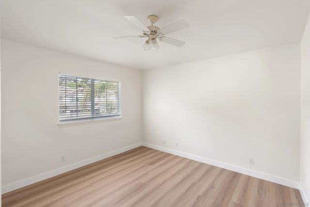 an empty room with wooden floor ceiling fan and windows