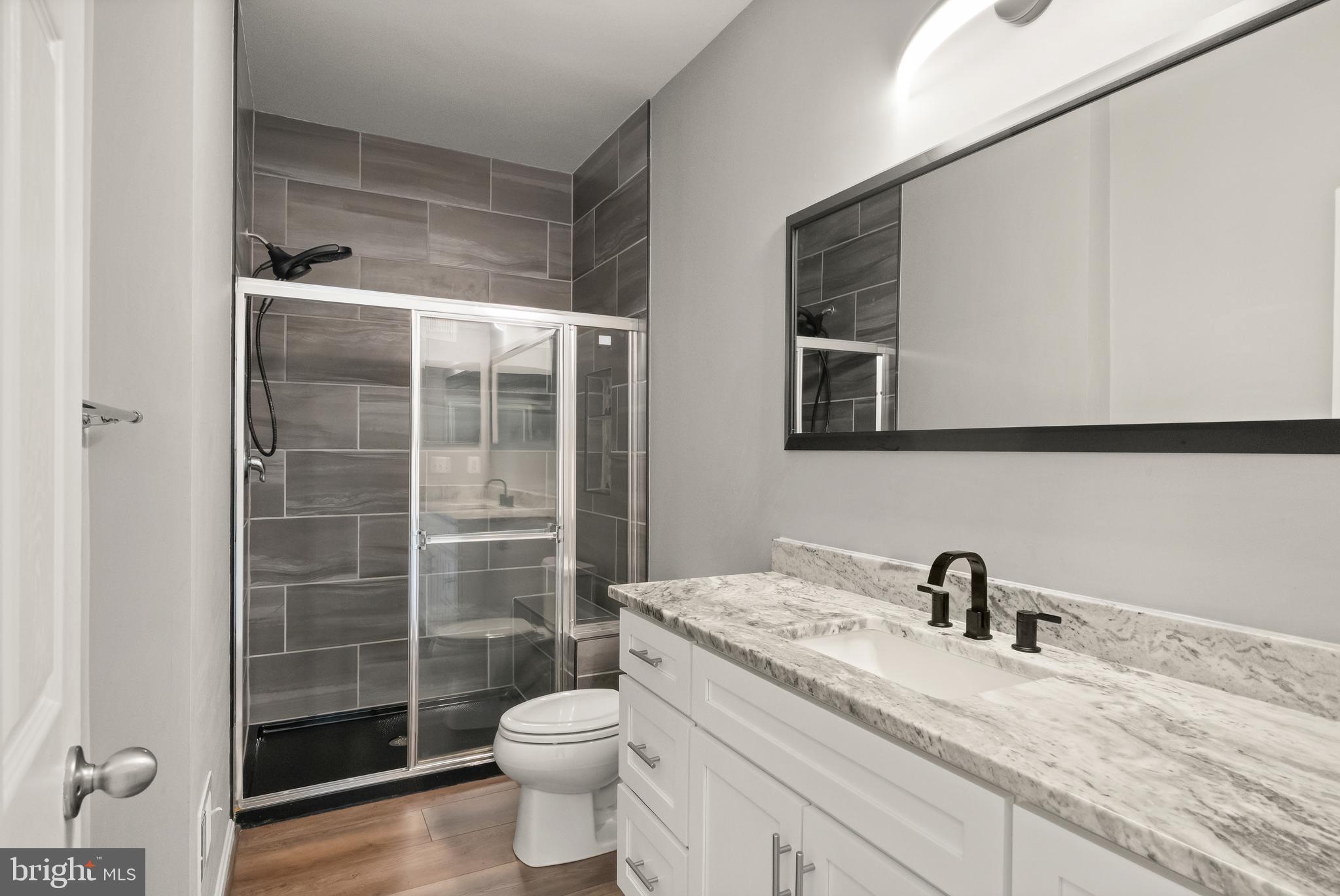 9541 Center Street Manassas, VA 20110 - Photo 15 of 41 a bathroom with a granite countertop sink a toilet a mirror and shower