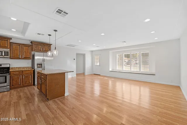 a large kitchen with stainless steel appliances granite countertop a large counter top a stove and a wooden floors