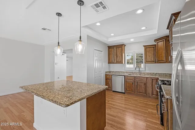 a kitchen with kitchen island granite countertop wooden floor and a refrigerator