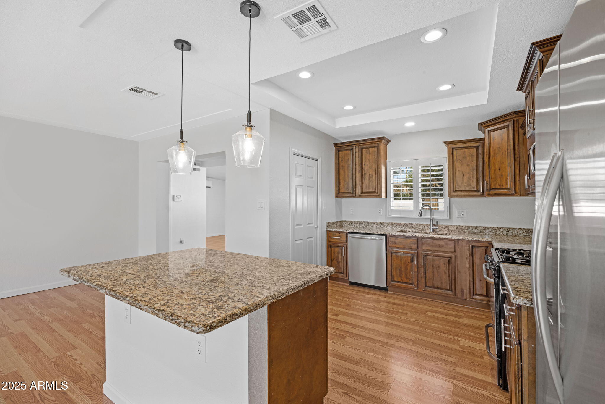 4020 North 44th Place Phoenix, AZ 85018 - Photo 6 of 17 a kitchen with kitchen island granite countertop wooden floor and a refrigerator