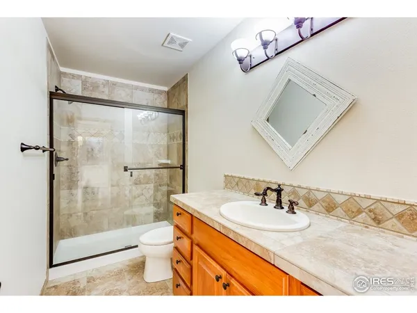 a bathroom with a granite countertop sink toilet a mirror and shower