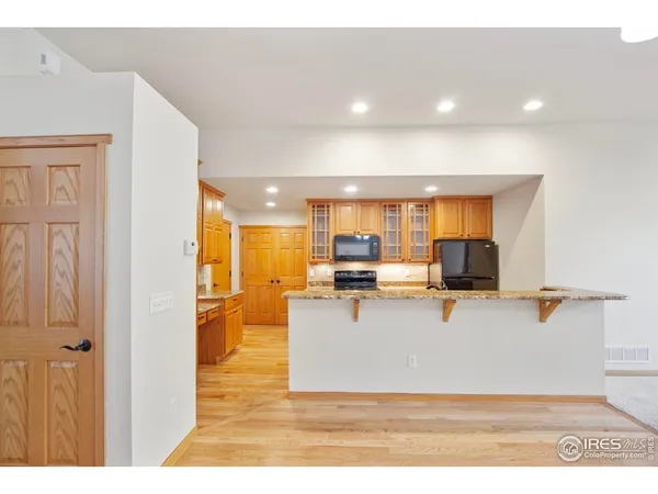a view of kitchen with kitchen island a sink a stove and a refrigerator with wooden floor