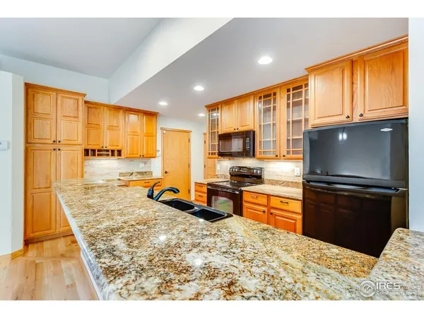 a kitchen with stainless steel appliances kitchen island granite countertop a refrigerator stove top oven and sink