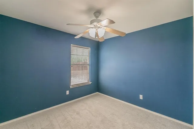an empty room with a window and a fan