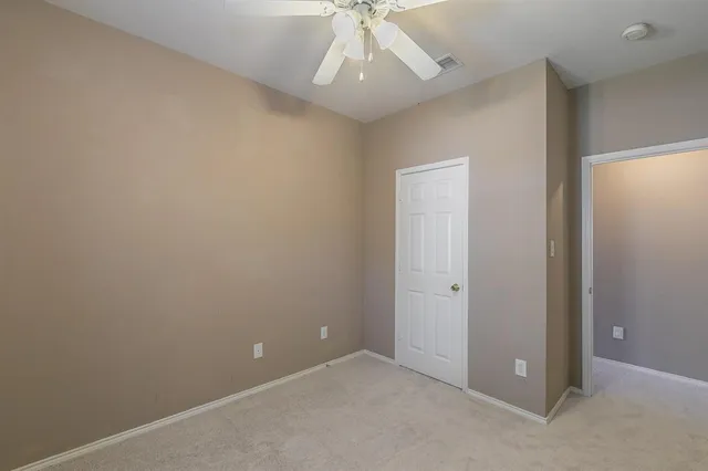 an empty room with a chandelier fan and windows