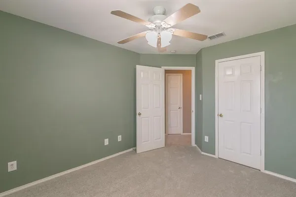 an empty room with a chandelier fan and a ceiling fan