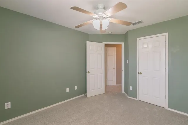 an empty room with a chandelier fan and a ceiling fan