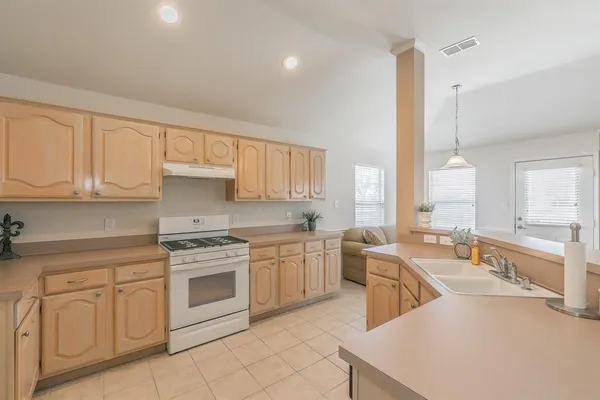 a kitchen with white cabinets sink and stove