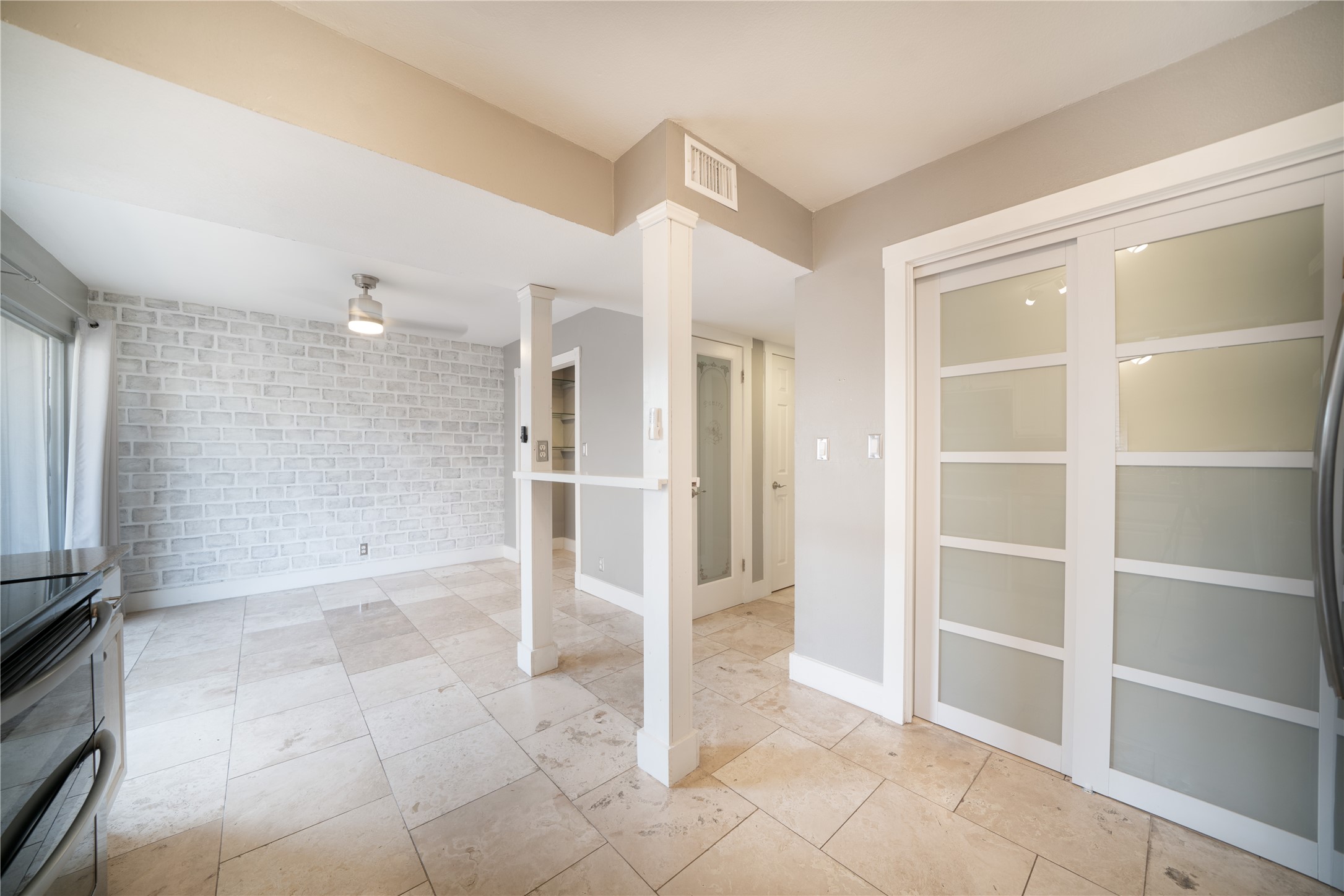 500 East Riverside Drive, Unit 242 Austin, TX 78704 - Photo 16 of 40 Unfurnished room featuring visible vents, brick wall, baseboards, ceiling fan, and ornate columns
