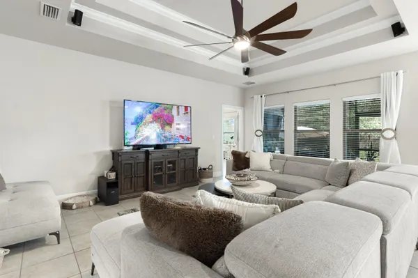 a living room with furniture a ceiling fan and a large window