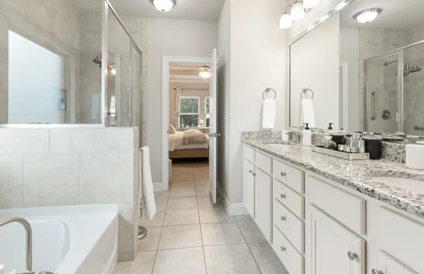 a spacious en suite bathroom with a granite countertop tub sink and mirror