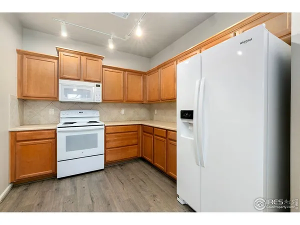 a kitchen with granite countertop wooden cabinets and white appliances