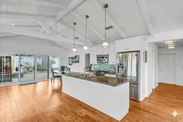 a kitchen with stainless steel appliances granite countertop a refrigerator a oven a stove and a sink with cabinets