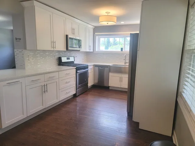 a kitchen with white cabinets and sink