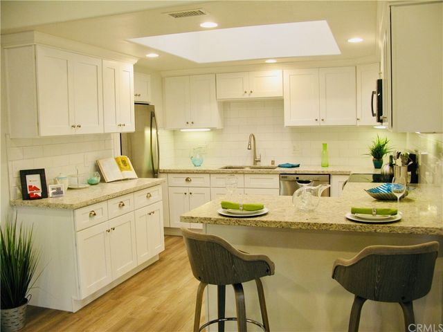 a kitchen with a sink a stove cabinets and chairs