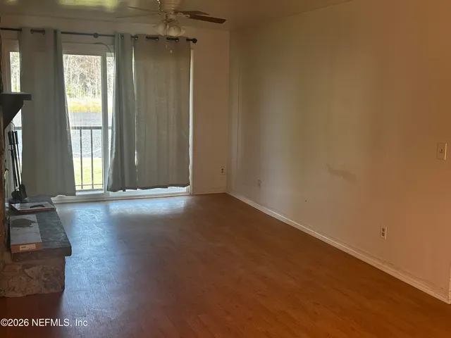 an empty room with wooden floor and windows